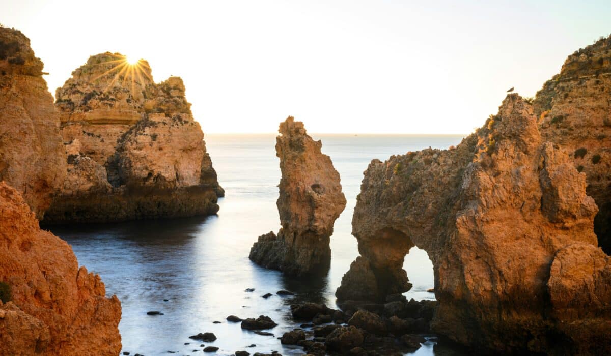 Een grote, stevige rots in het heldere water van de Algarve in de zomer, symbool voor het opbouwen van zelfvertrouwen met hypnotherapie.